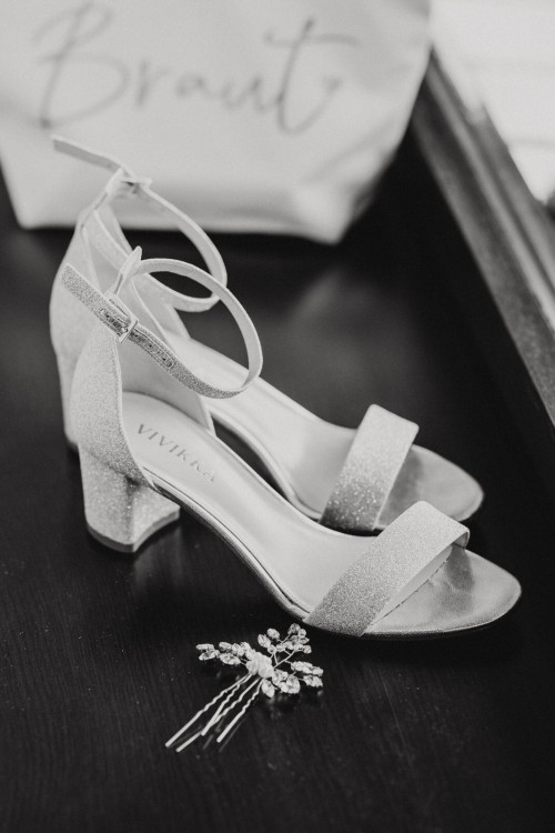 Ein schwarz-weißes Bild von Brautschuhen und Haarschmuck.