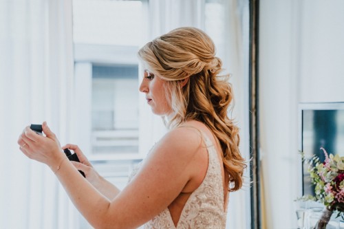 Eine Braut sprüht sich mit einem Parfüm an.