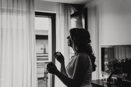 Ein schwarz-weißes Bild einer Frau wie sie sich mit einem Parfüm ansprüht.