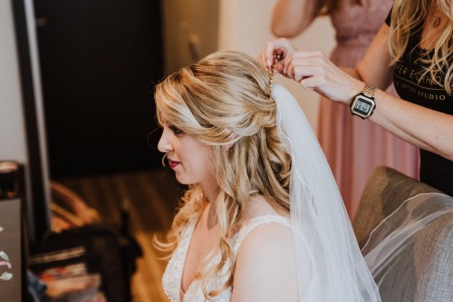 Eine Frau steck einer Braut einen Schleier in die Haare.