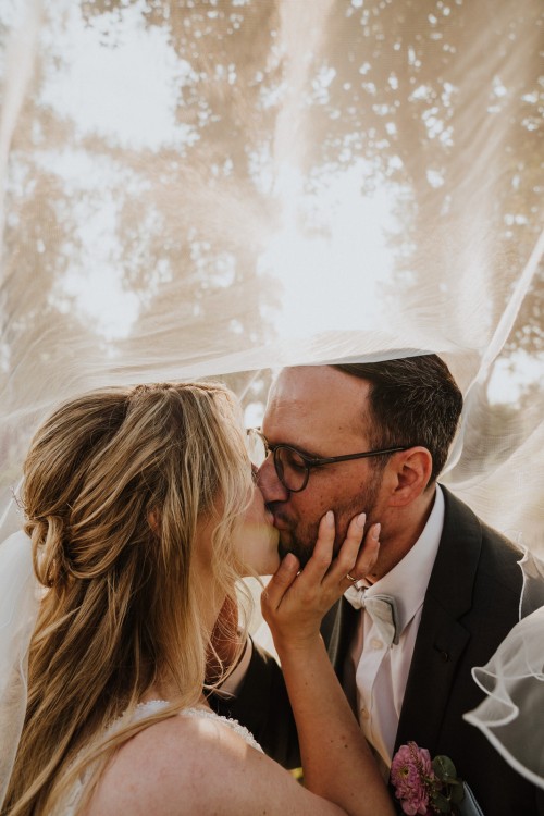 Ein Brautpaar küsst sich unter dem Schleier.