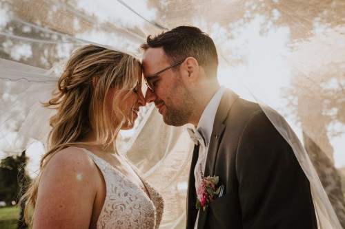 Ein Brautpaar steht unter einem Schleier.