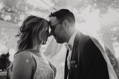 Ein schwarz-weißes Bild von einem Brautpaar unter einem Schleier.