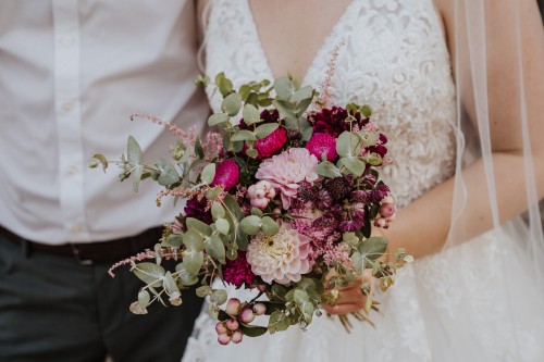 Ein Brautstrauß mit Eukalyptus und pinken Blumen.