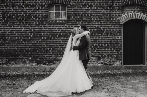 Das Brautpaar umarmt und küsst sich auf dem Feltgenhof