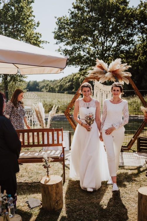 Annika und Claudia bei ihrer intimen Trauung unter einem herbstlichen Hochzeitsbogen. Annika und Claudia während ihrer emotionalen Trauung unter einem romantischen Bogen im herbstlichen Ambiente.
